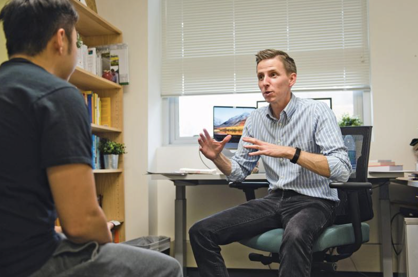 faculty member Seth Stewert works with student in his office