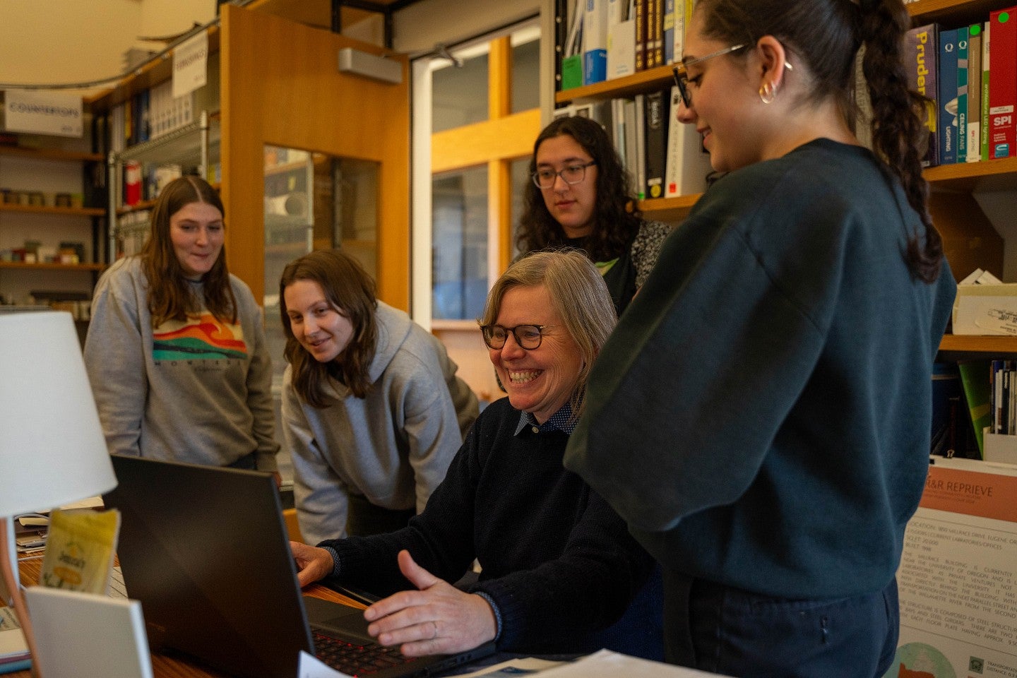 christina bollo sits at computer with students