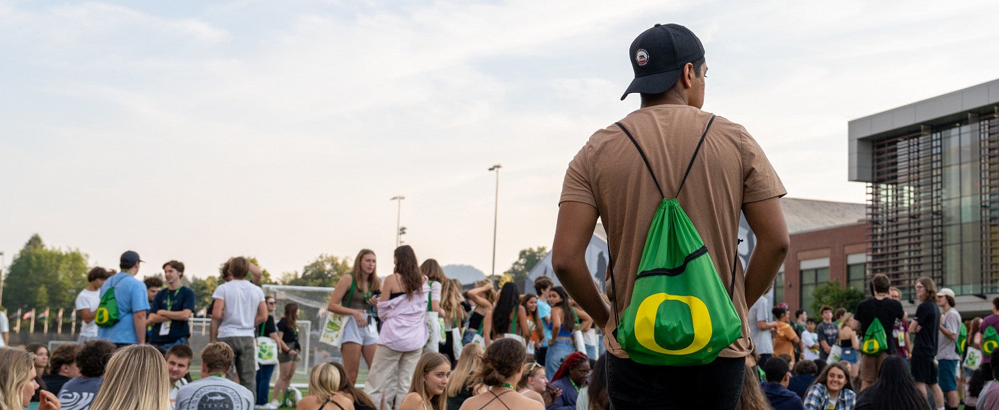 student with UO gym bag stand center in front of crowd of students sitting