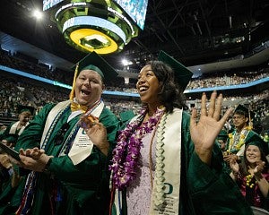 two students at the UO commencement ceremony in Matthew Knight Arena
